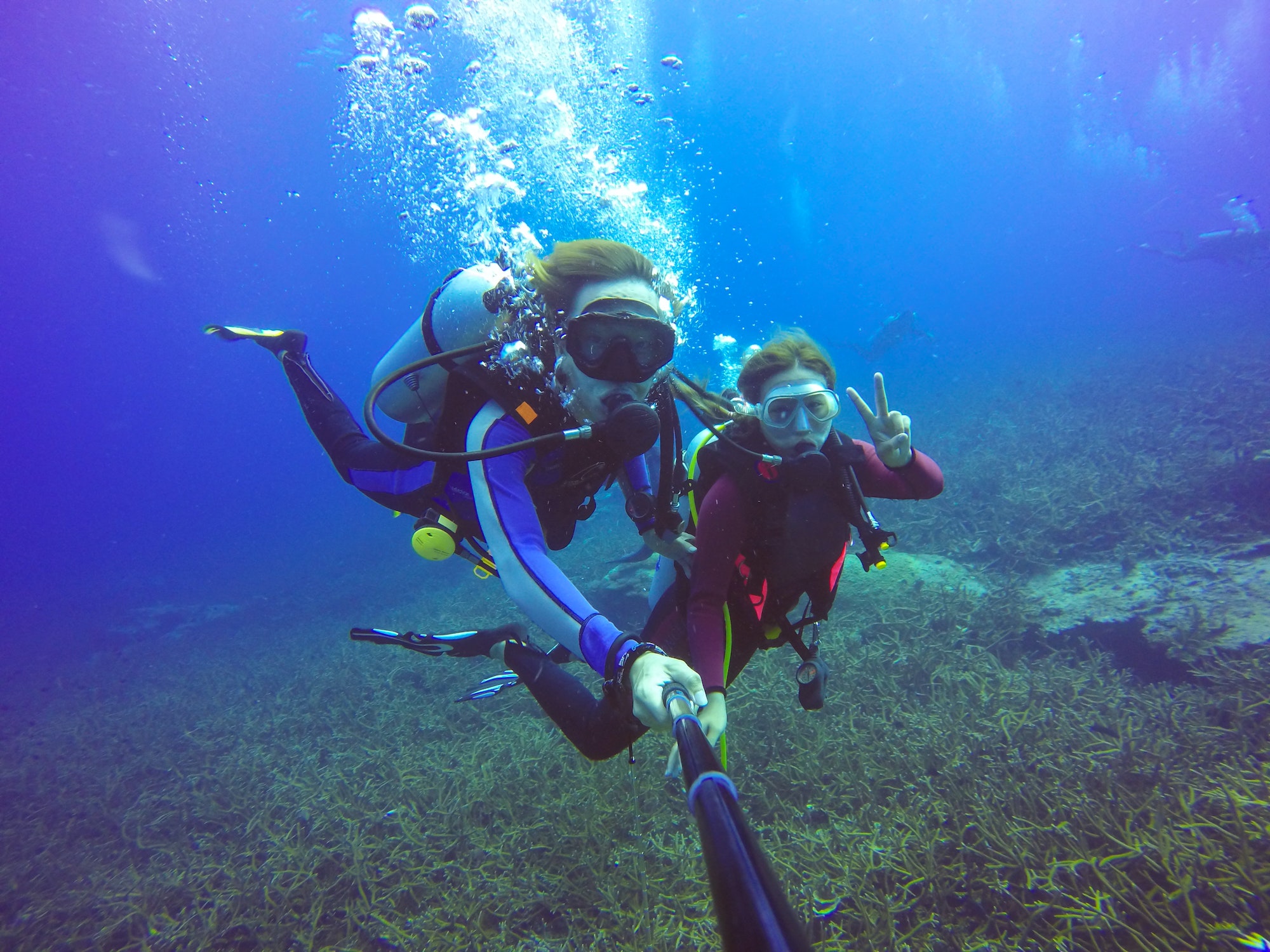 Underwater scuba diving selfie shot with selfie stick. Deep blue sea. Wide angle shot.